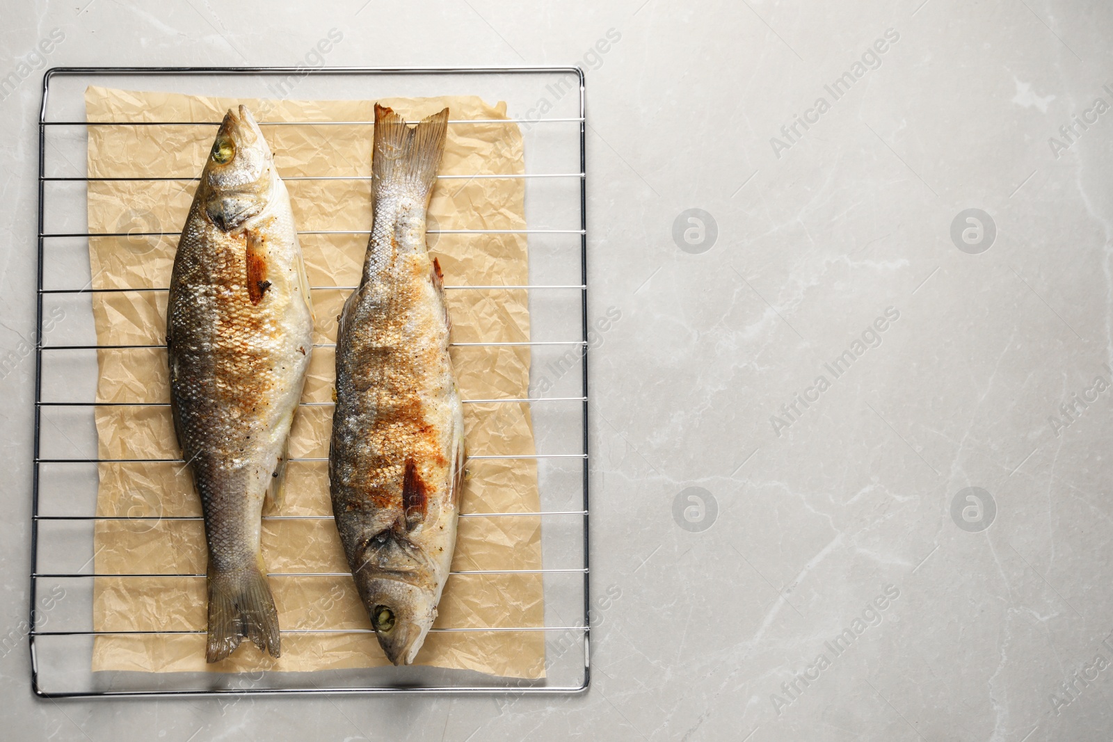 Photo of Baked fish on light marble table, top view. Space for text