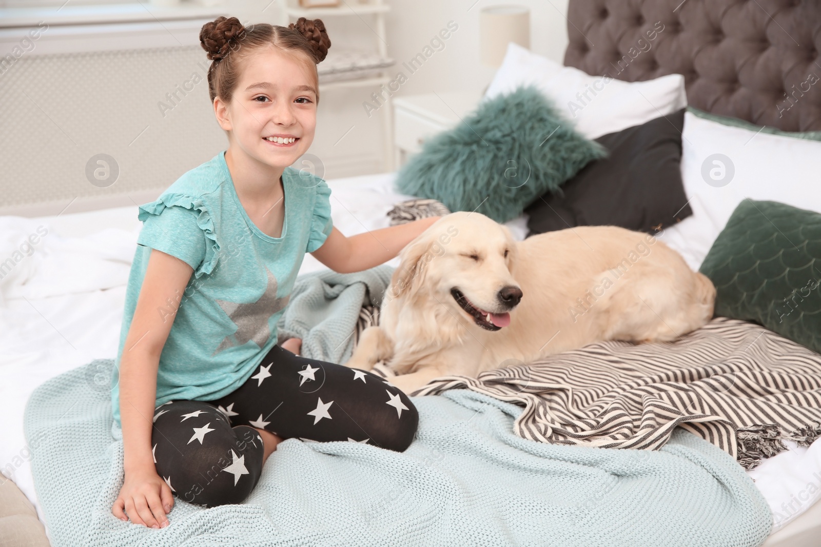 Photo of Cute little child with her pet on bed at home