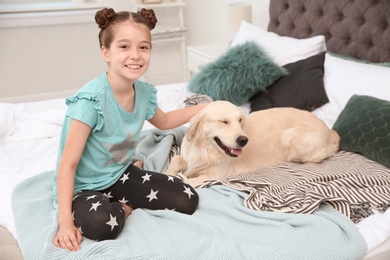 Cute little child with her pet on bed at home