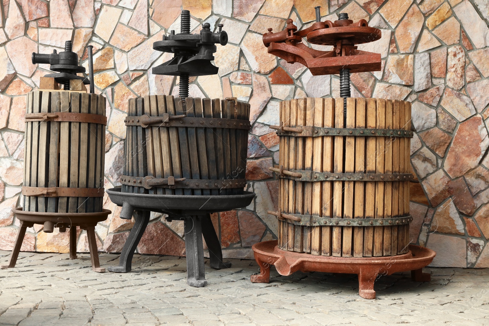 Photo of Metal winepresses in wooden barrels near stone wall outdoors