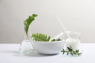 Natural ingredients and laboratory glassware for organic cosmetic product on white table