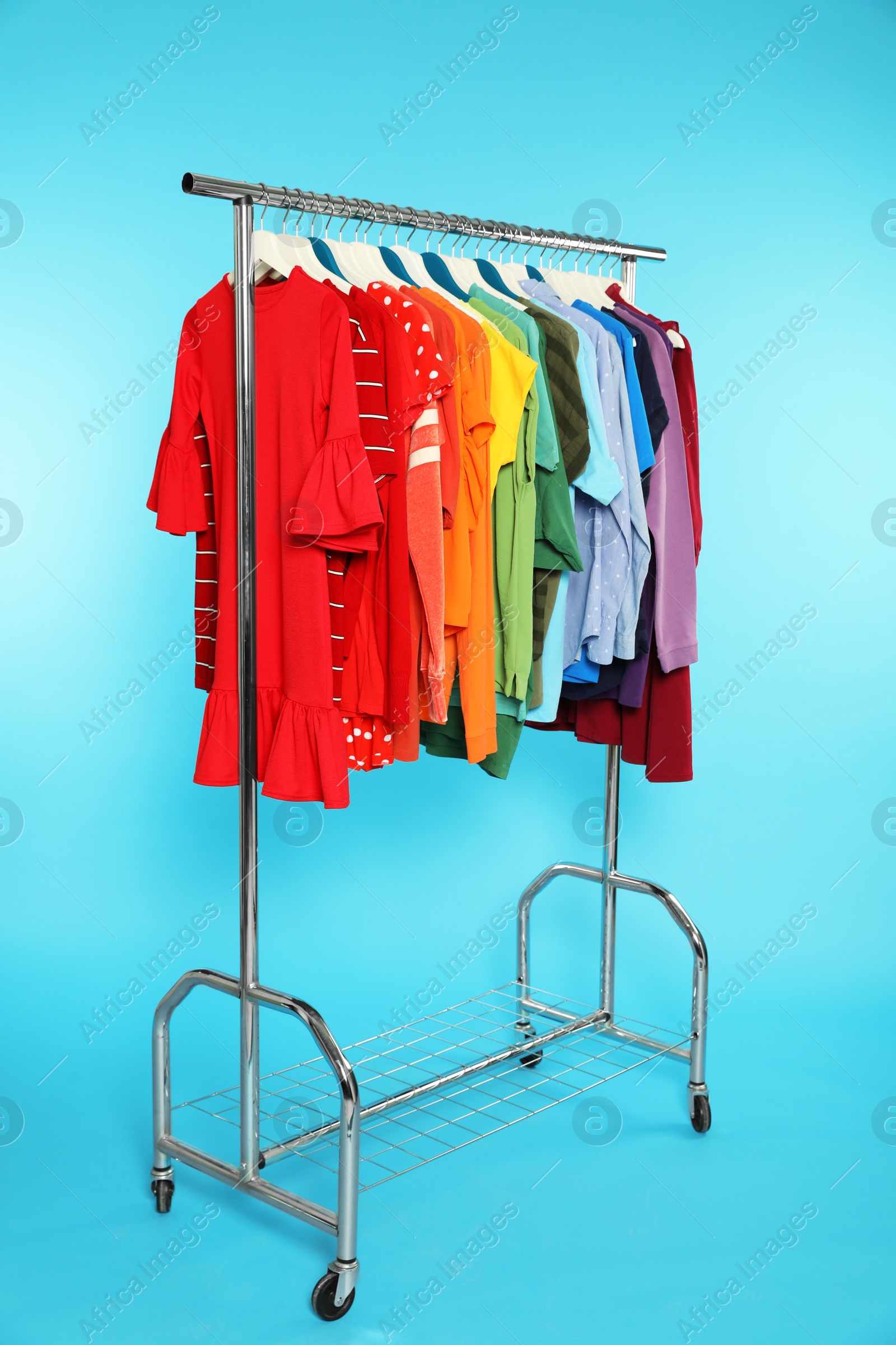 Photo of Wardrobe rack with different bright clothes on color background