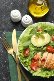 Photo of Delicious salad with chicken, cherry tomato and avocado served on grey textured table, flat lay