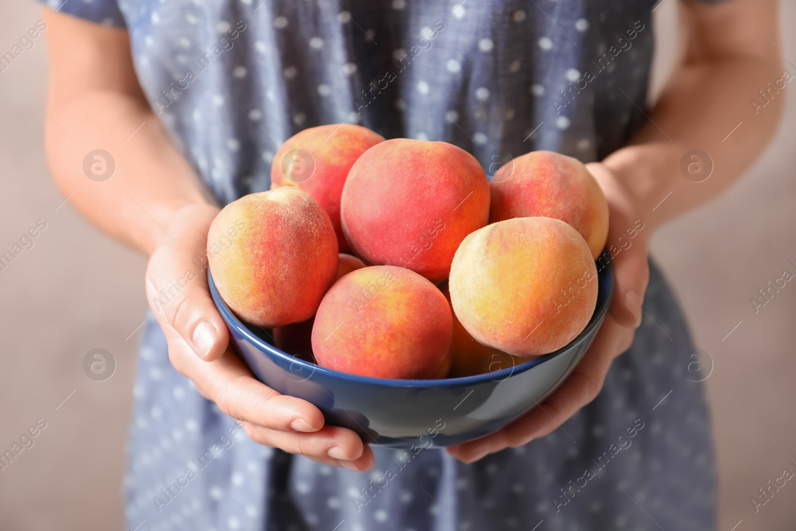 Photo of Woman holding bowl with delicious ripe peaches, closeup