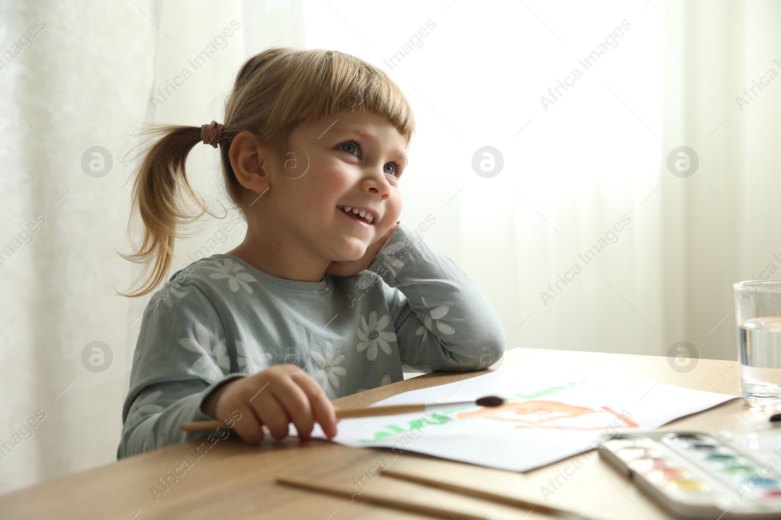 Photo of Cute little girl drawing at wooden table indoors. Child`s art