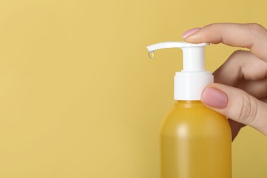 Photo of Woman using cleansing gel on pale yellow background, closeup. Space for text