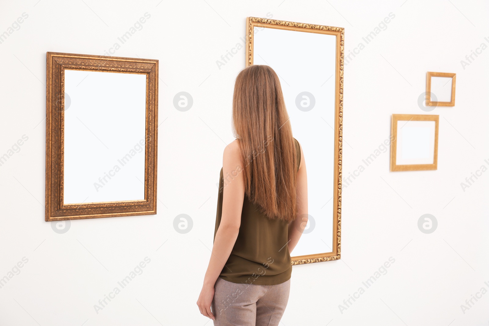 Photo of Young woman viewing exposition in modern art gallery