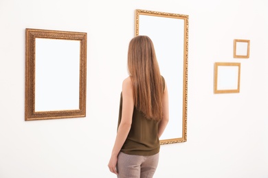 Photo of Young woman viewing exposition in modern art gallery