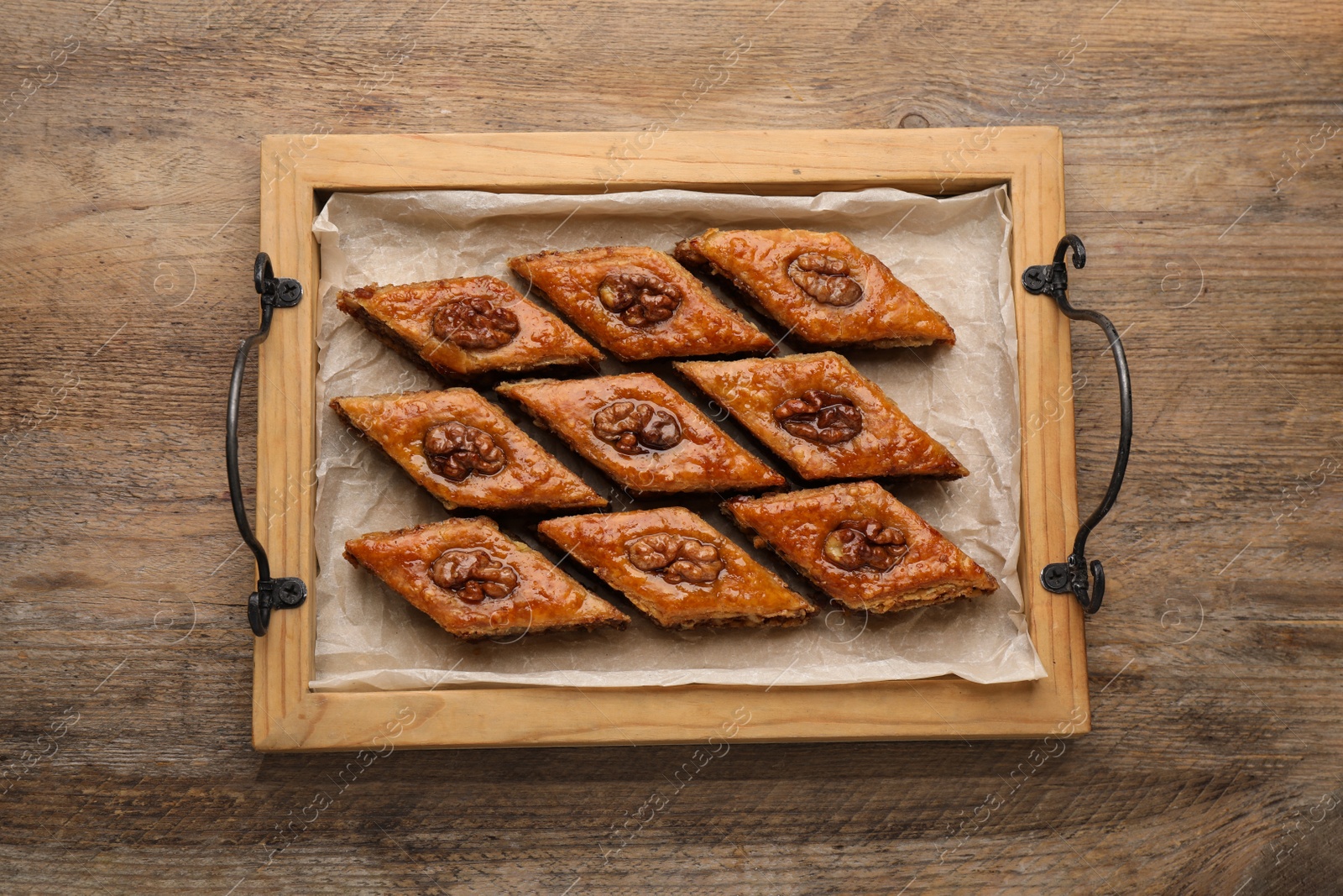 Photo of Delicious honey baklava with walnuts on wooden table, top view