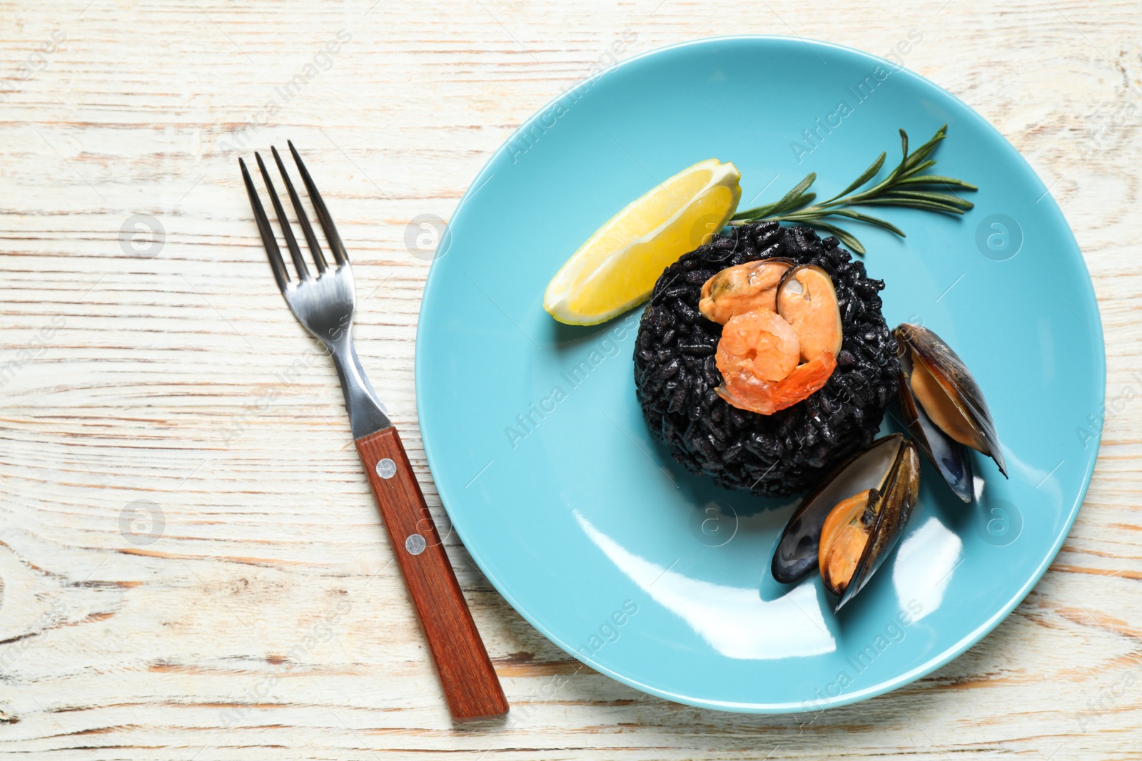 Photo of Delicious black risotto with seafood on white wooden table, top view