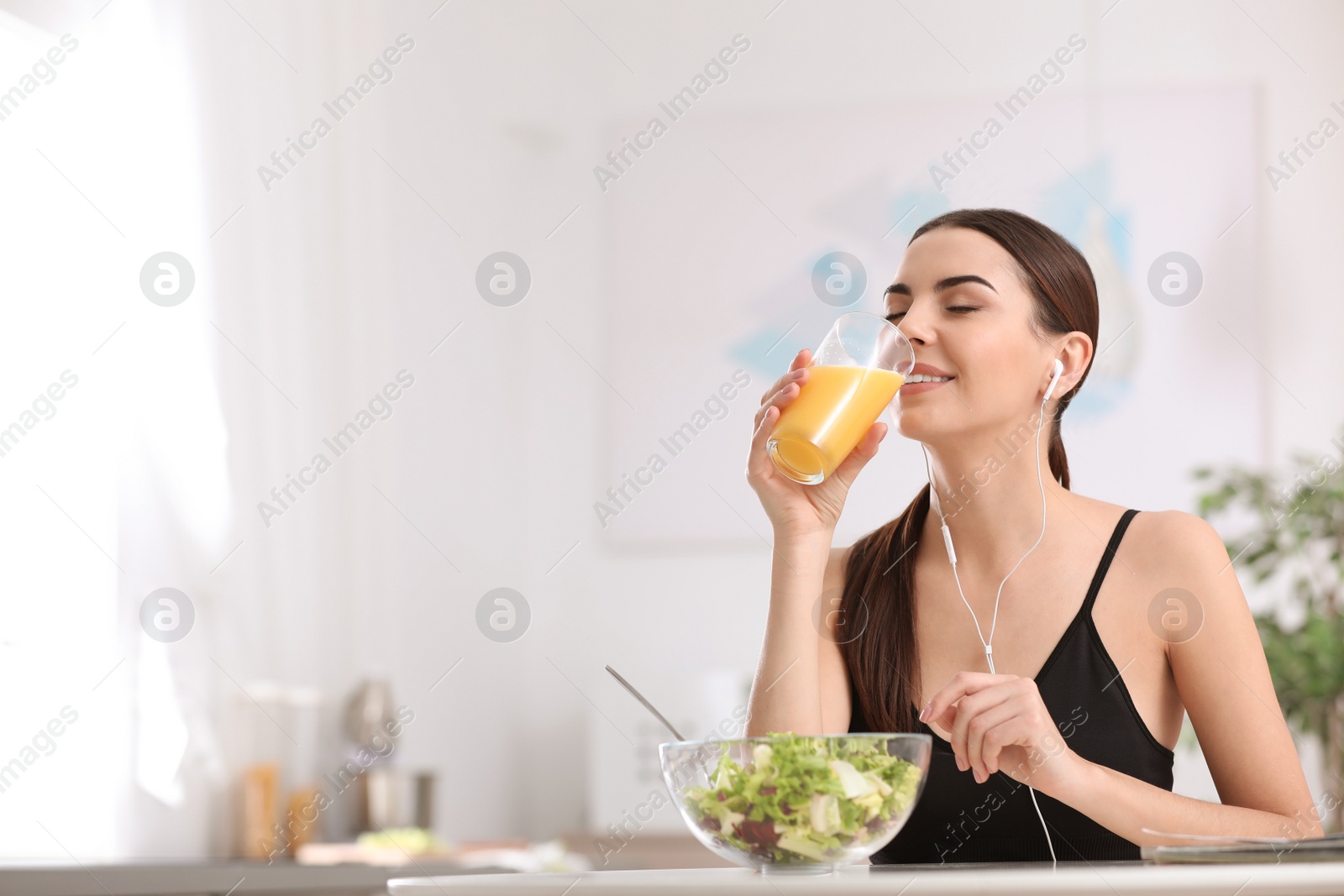 Photo of Young woman in fitness clothes having healthy breakfast at home. Space for text