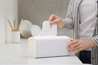 Woman taking paper towel from package in kitchen, closeup