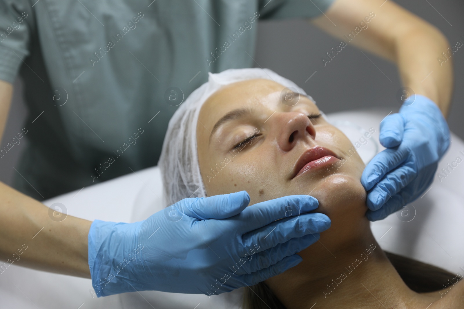 Photo of Young woman receiving facial massage in salon