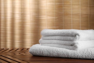 Photo of Stacked soft towels on wooden table indoors
