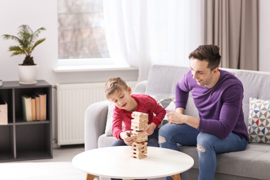 Photo of Dad and his son playing board game at home