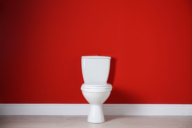 Photo of Toilet bowl near color wall in restroom. Space for text