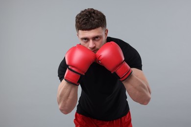 Photo of Man in boxing gloves on grey background