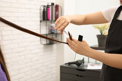 Photo of Professional stylist cutting client's hair in salon, closeup