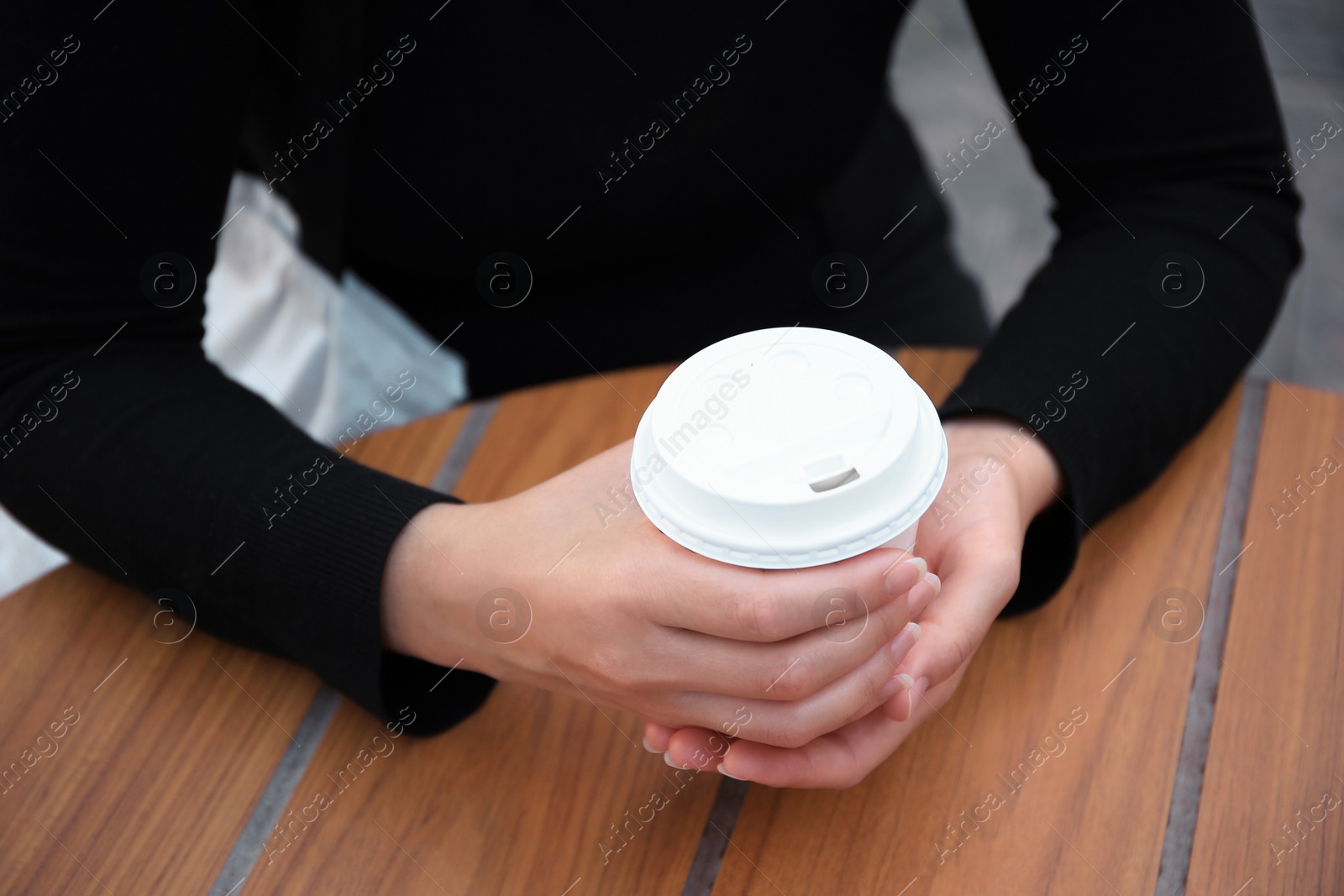 Photo of Woman with cardboard cup of coffee at table, closeup