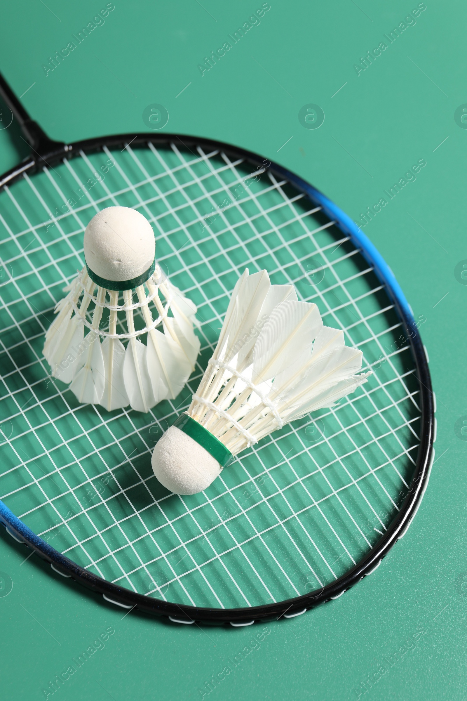 Photo of Feather badminton shuttlecocks and racket on green background