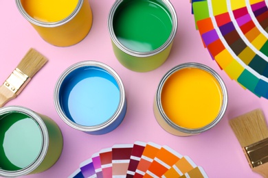 Flat lay composition with paint cans, brushes and color palettes on pink background