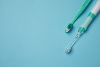 Photo of Electric and plastic toothbrushes on turquoise background, flat lay. Space for text