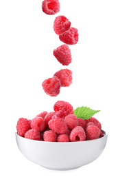 Fresh ripe tasty raspberries falling into bowl on white background