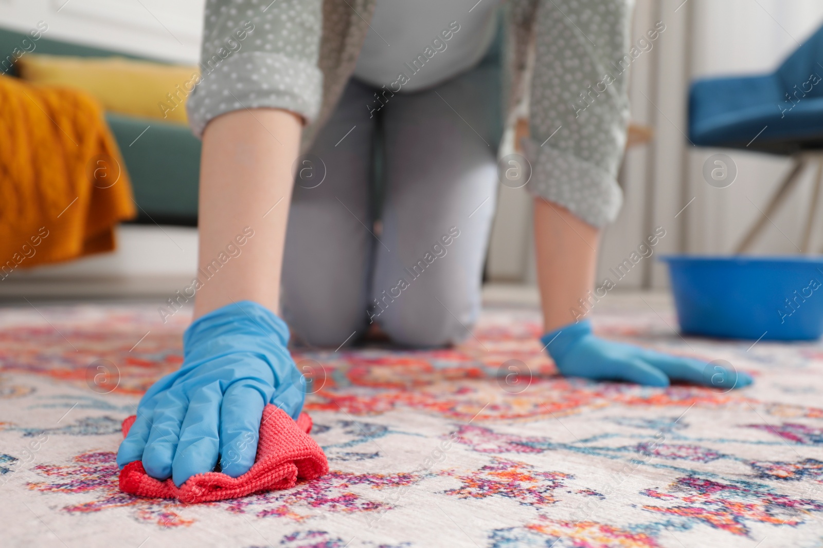 Photo of Woman in rubber gloves cleaning carpet with rag indoors, closeup. Space for text