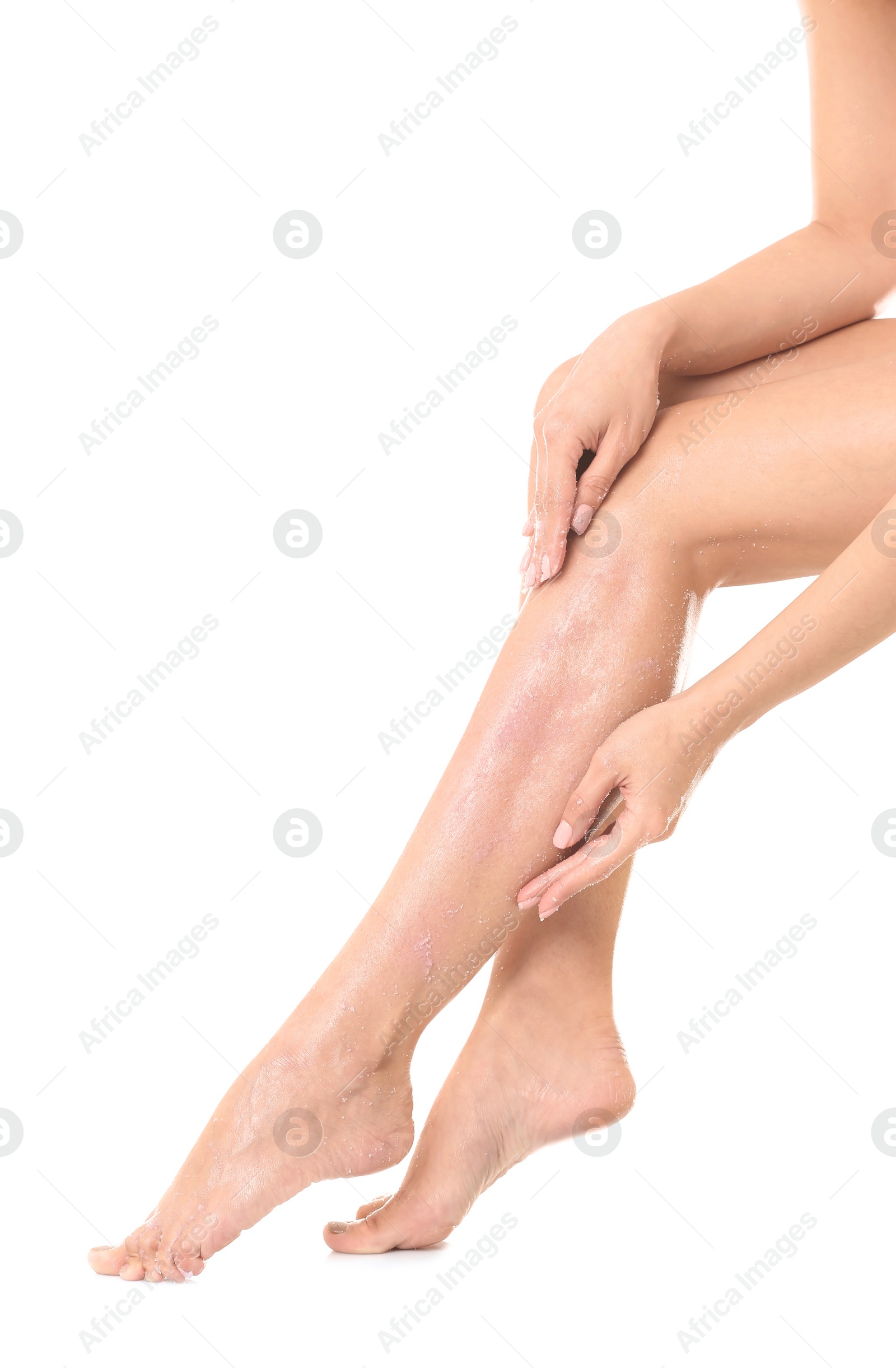 Photo of Young woman applying body scrub on leg against white background