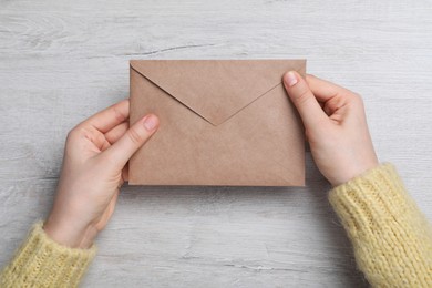 Photo of Woman with brown envelope at wooden table, top view