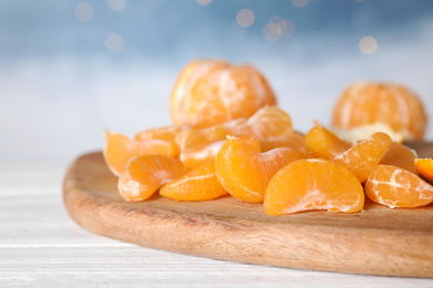 Segments of fresh juicy tangerines on white wooden table, closeup