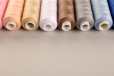 Photo of Different sewing threads on light grey background. Space for text
