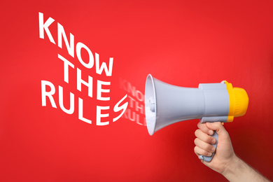 Image of Man using megaphone to say Know the rules on red background, closeup