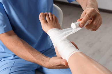 Photo of Doctor applying bandage onto patient's foot in hospital, closeup