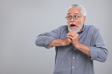 Photo of Portrait of embarrassed senior man on light grey background, space for text