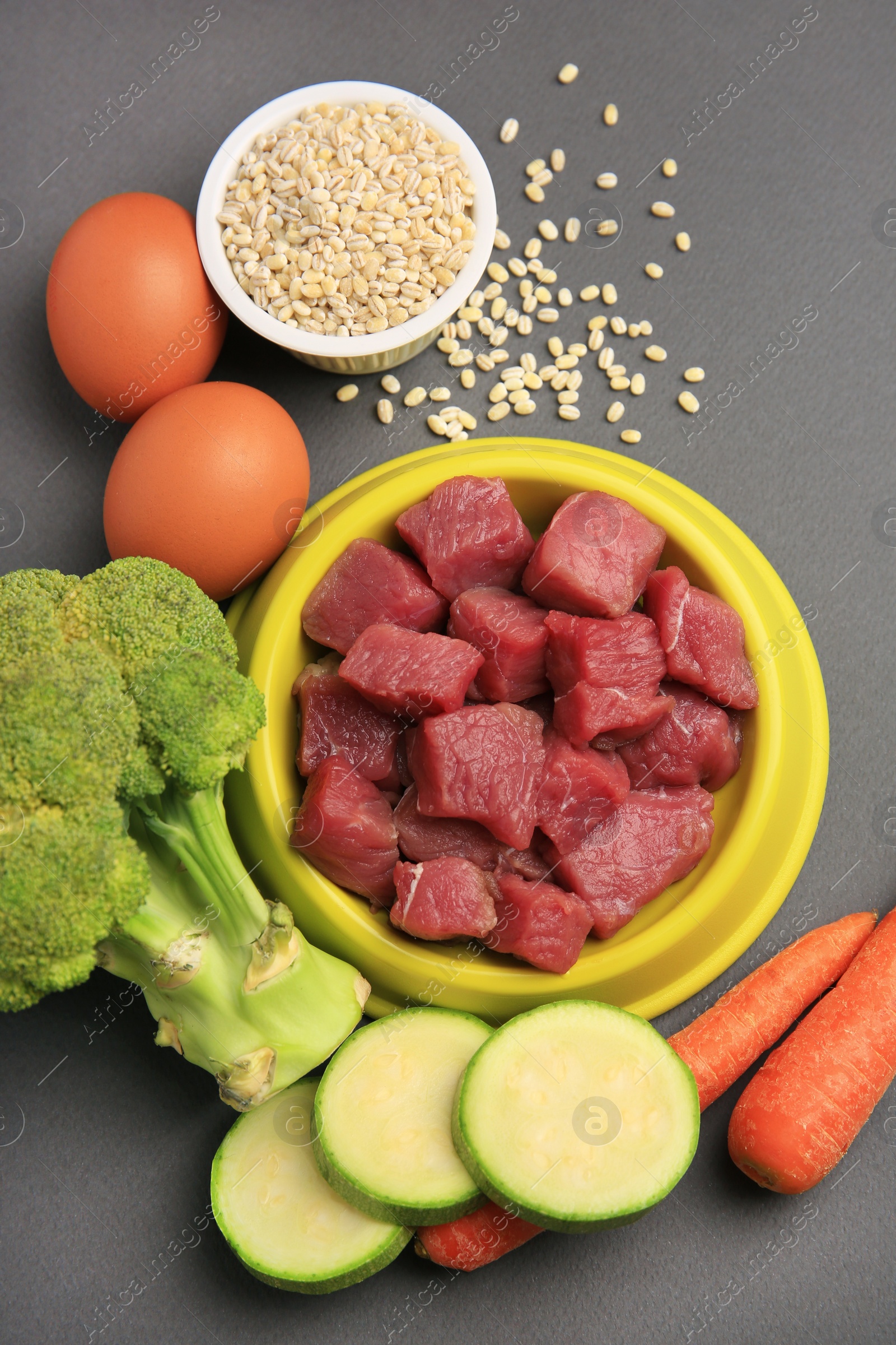 Photo of Raw meat in bowl and healthy products for pet on black background, flat lay