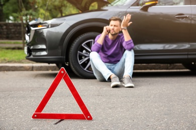 Photo of Emergency stop sign and man near broken car on background