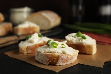 Photo of Bread with cream cheese and green onion on black table