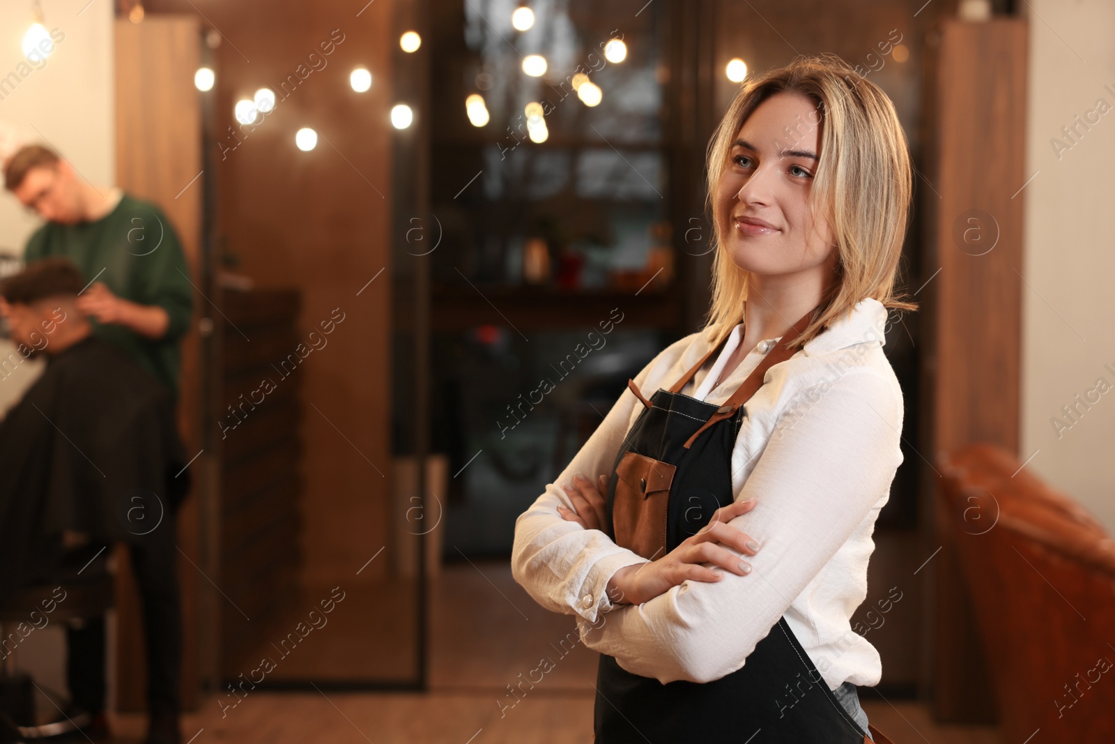 Photo of Portrait of professional hairdresser wearing apron in beauty salon, space for text