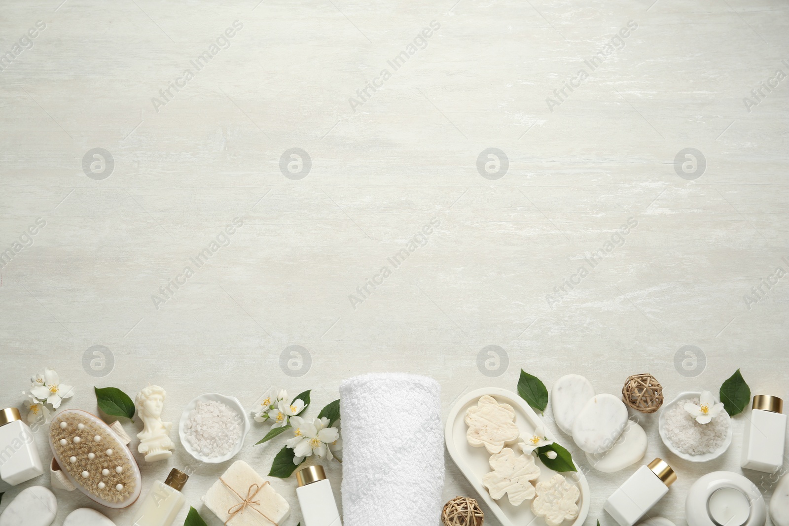 Photo of Jasmine flowers and set of spa essentials on white wooden table, flat lay. Space for text