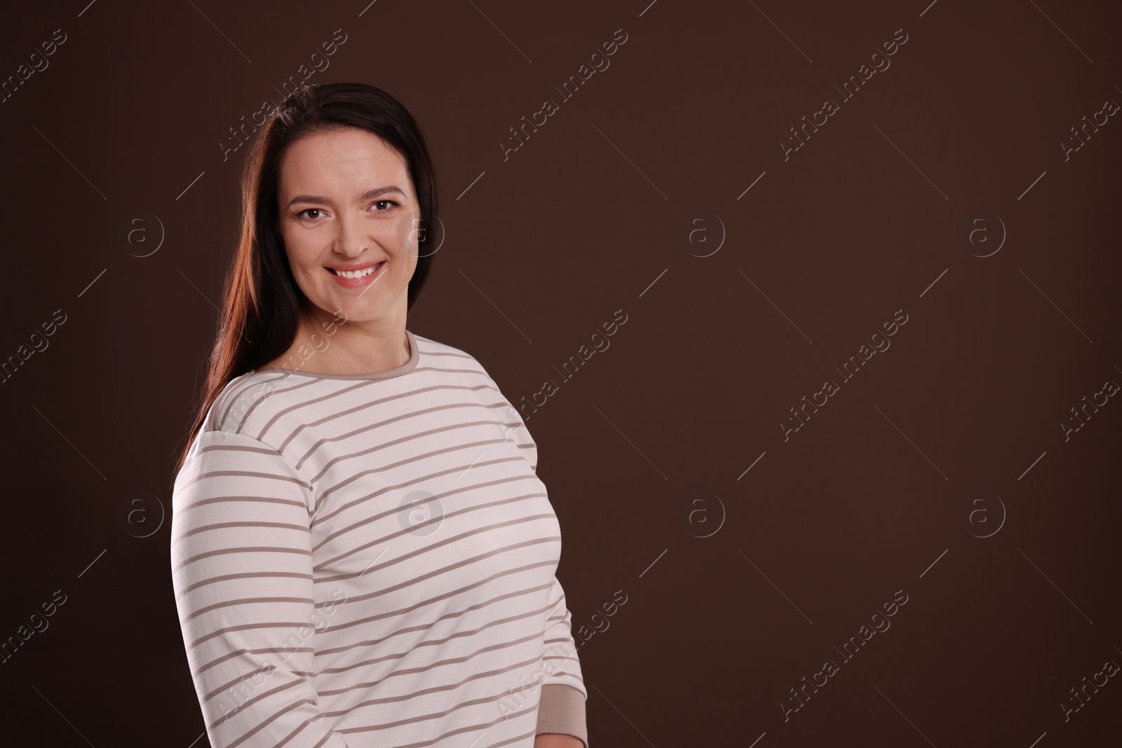 Photo of Beautiful overweight woman with charming smile on brown background. Space for text