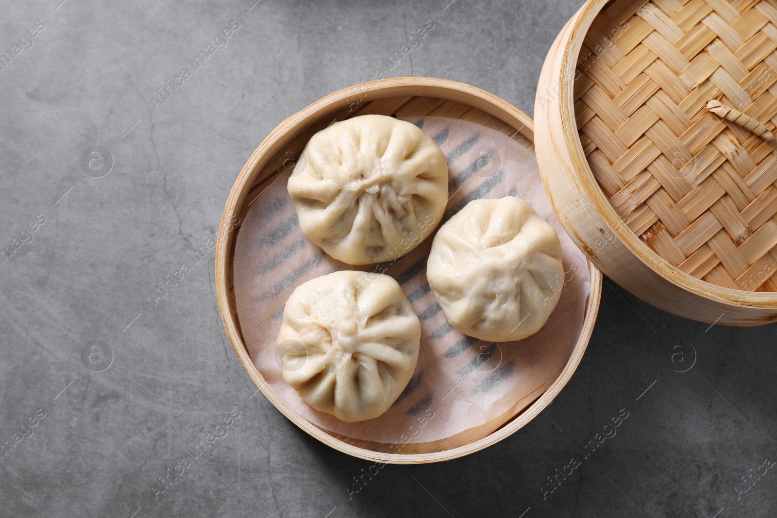 Photo of Delicious bao buns (baozi) on grey textured table, top view
