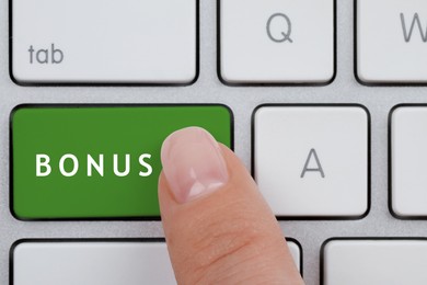 Woman pressing green Bonus button on keyboard, closeup