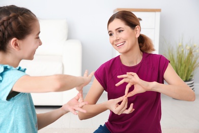 Hearing impaired mother and her child talking with help of sign language indoors