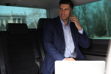 Handsome man talking on phone in modern car