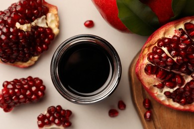 Glass jar of tasty pomegranate sauce and fresh ripe fruits on white background, flat lay