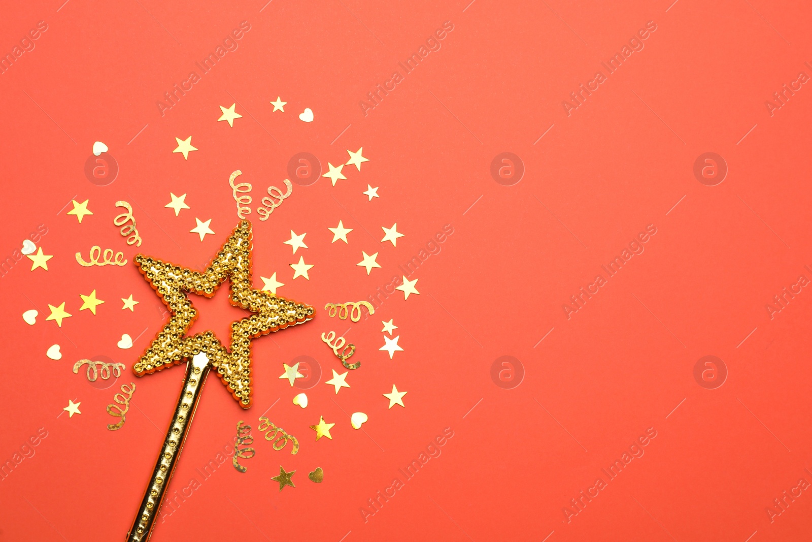 Photo of Beautiful golden magic wand and confetti on coral background, flat lay. Space for text