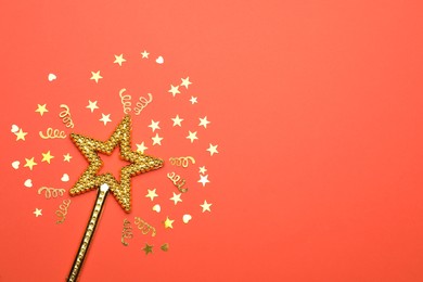 Photo of Beautiful golden magic wand and confetti on coral background, flat lay. Space for text