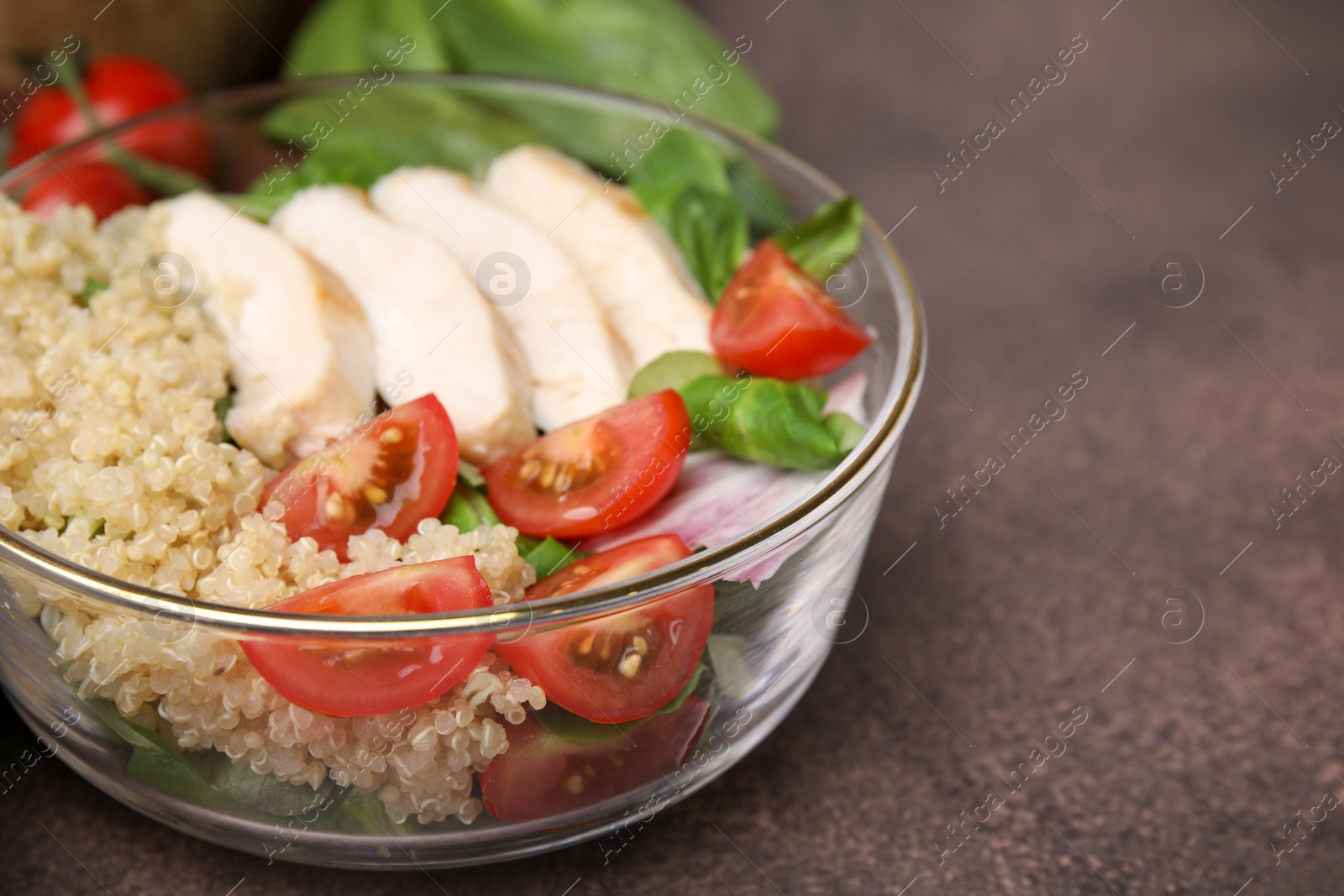 Photo of Delicious quinoa salad with chicken and cherry tomatoes served on grey textured table, closeup. Space for text