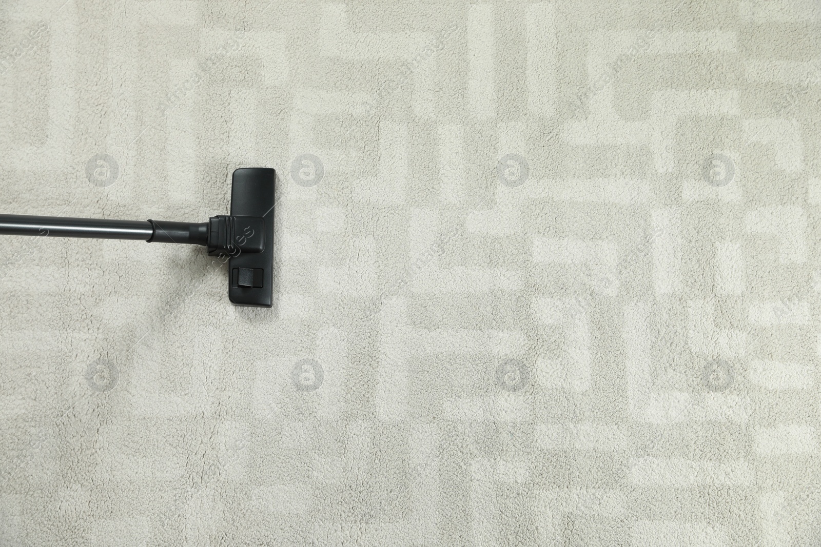 Photo of Removing dirt from white carpet with modern vacuum cleaner, top view. Space for text